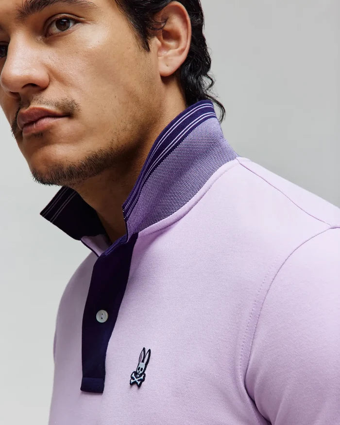 Mens Kenyon Lightweight Pique Polo in light lavender, featuring a classic fit, dark purple placket, striped collar, and small embroidered Psycho Bunny skull logo on the left chest.