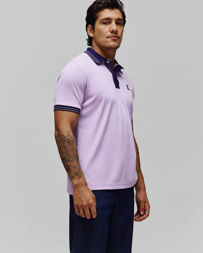 Mens Kenyon Lightweight Pique Polo in lavender, classic fit, with a navy ribbed collar, white tipping, two-button placket, navy striped cuffs, and an embroidered Psycho Bunny skull logo on the left chest.