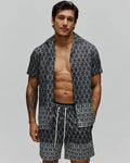 Mens Keon Tencel Shirt, a relaxed fit black short-sleeve button-up with an all-over white Psycho Bunny skull logo pattern, paired with matching shorts featuring white drawstrings.