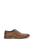 The Vince Camuto Men’s Lazzarp Wingtip Brogue, a brown luxe leather dress shoe featuring brogue detailing, dark laces, and a low heel, is displayed in profile on a white background—an ideal choice for elevating any office outfit.