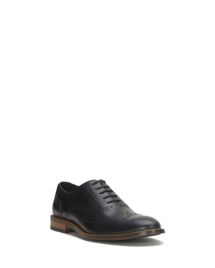 A single Vince Camuto Men’s Lazzarp Wingtip Brogue in black luxe leather, featuring decorative brogue detailing and a brown heel, sits against a plain white background.