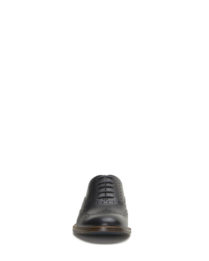 A single Vince Camuto Men’s Lazzarp Wingtip Brogue dress shoe, crafted from luxe black leather and shown from the front on a white background. This shoe features elegant brogue detailing, classic closed lacing, and provides refined style suitable for any occasion.