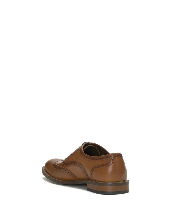 The Vince Camuto Men’s Lazzarp Wingtip Brogue, crafted from luxurious brown leather with signature brogue detailing, is displayed at an angle to showcase the back and side against a white background.
