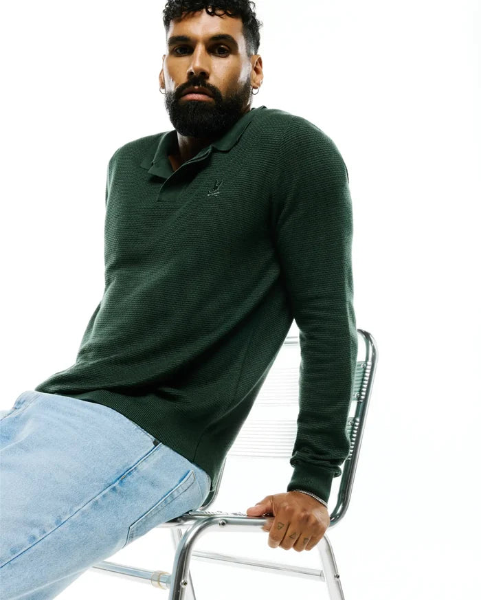 MENS LEROY LONG SLEEVE KNIT POLO in deep forest green, featuring a textured knit fabric, classic collar, ribbed cuffs, and a small embroidered Psycho Bunny skull logo on the left chest.