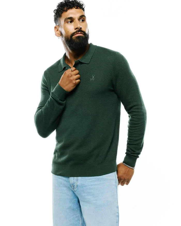 Dark green Mens Leroy Long Sleeve Knit Polo, classic fit, featuring a textured knit fabric, polo collar, ribbed cuffs and hem, and a small embroidered Psycho Bunny skull logo on the left chest.
