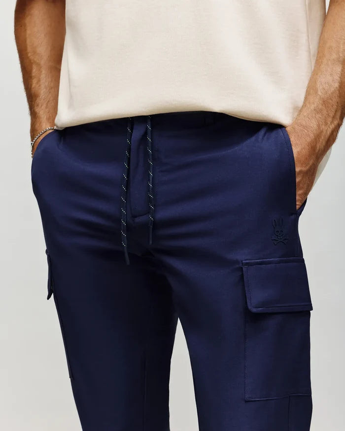 Mens Lloyd Cargo Jogger in navy blue, featuring a relaxed fit, smooth fabric, white speckled drawstring, side cargo pockets, and a small tonal embroidered Psycho Bunny skull logo on the left thigh.