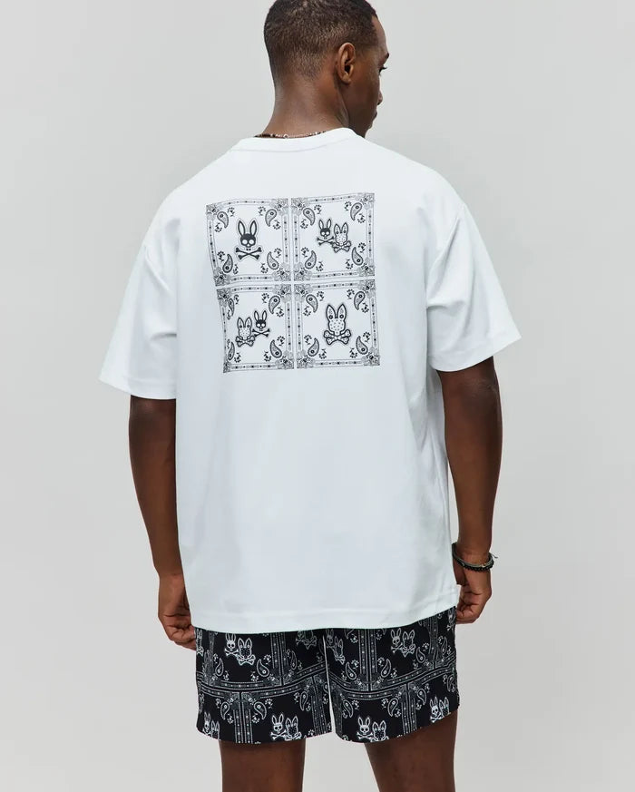 White Mens Luke Back Graphic Tee, relaxed jersey tee with a large black bandana graphic and four Psycho Bunny skull logos on the back, paired with black relaxed shorts with all-over white bandana-bunny skull pattern.