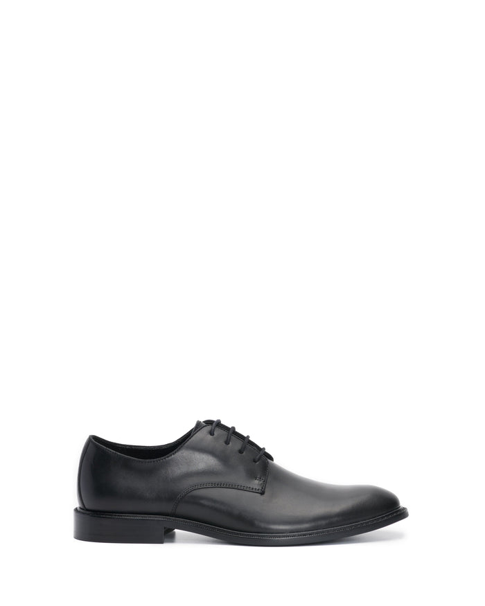 The Vince Camuto Men’s Lyre Derby is a classic black leather dress shoe with laces, shown from the side against a white background.