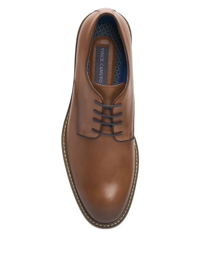 A top view of the Vince Camuto Men’s Lyre Derby brown leather dress shoe with brown laces and a stitched sole, displayed on a white background. The classic design is complemented by a dark leather insole embossed with the Vince Camuto brand name.