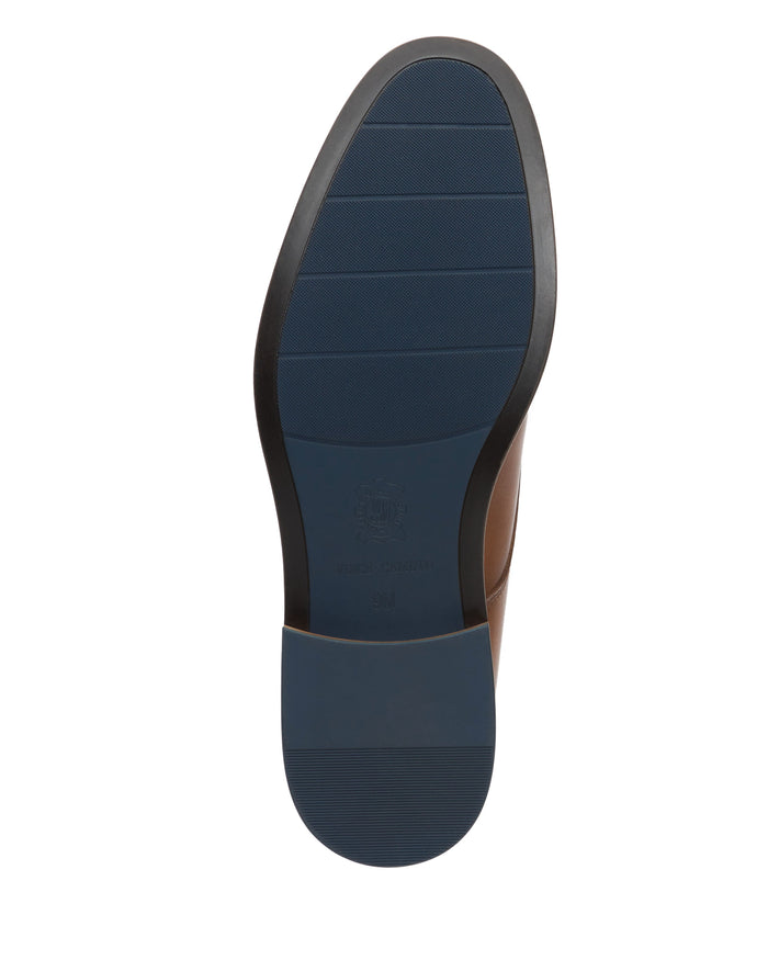 The bottom view of the Vince Camuto Men’s Lyre Derby shoe showcases a blue, textured rubber sole with black trim, subtle horizontal grooves, and branded detailing near the heel—highlighting its timeless dark leather design.