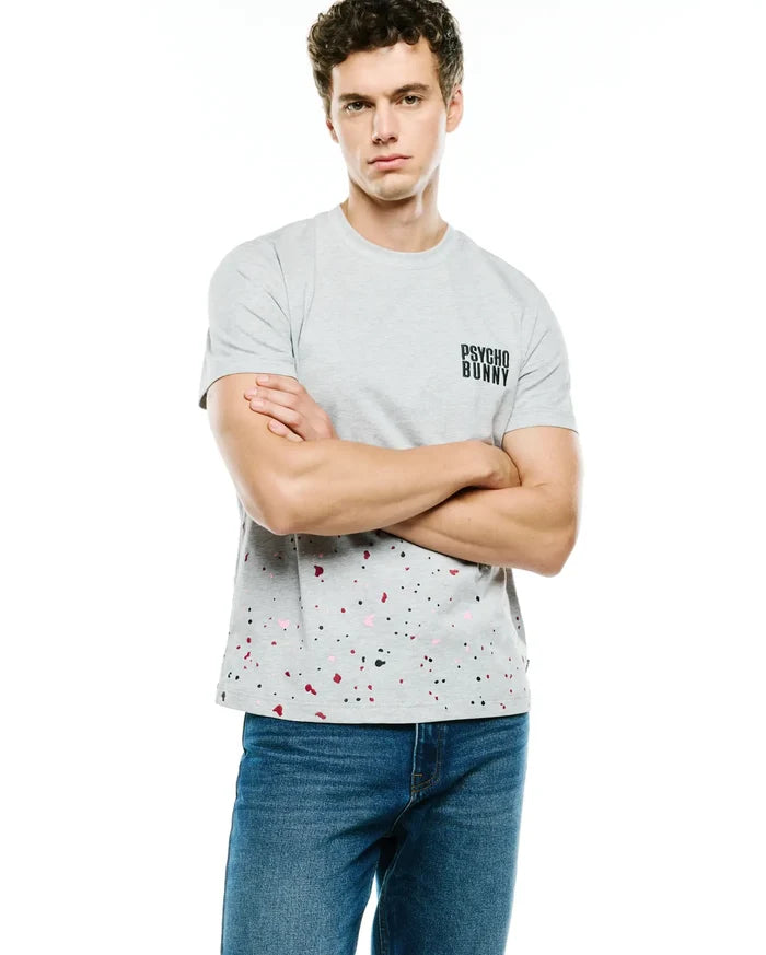 Mens Malcolm Graphic Tee, a grey classic fit jersey t-shirt featuring a small black Psycho Bunny text logo on the chest and a vibrant black, pink, and red paint splatter pattern on the lower half.