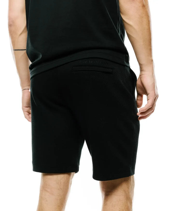 Mens Marc Textured Short, a black, relaxed-fit short crafted from a distinctive textured knit fabric, featuring subtle tonal embroidered Psycho Bunny branding on the back waistband.