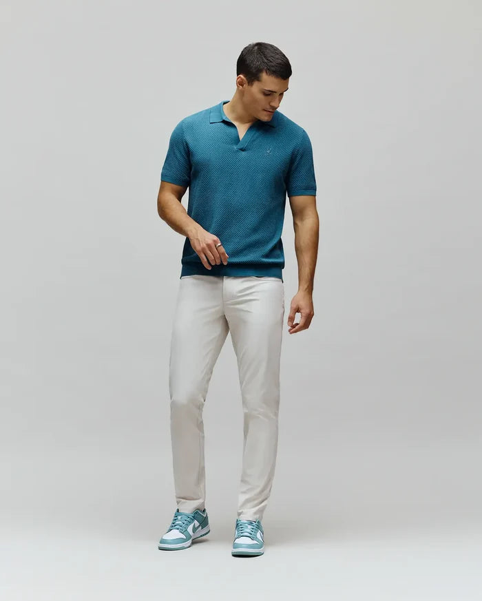 Teal textured knit polo with a tonal embroidered Psycho Bunny skull logo on the chest, paired with slim fit light beige Mens Maverick 10k Step Pant.