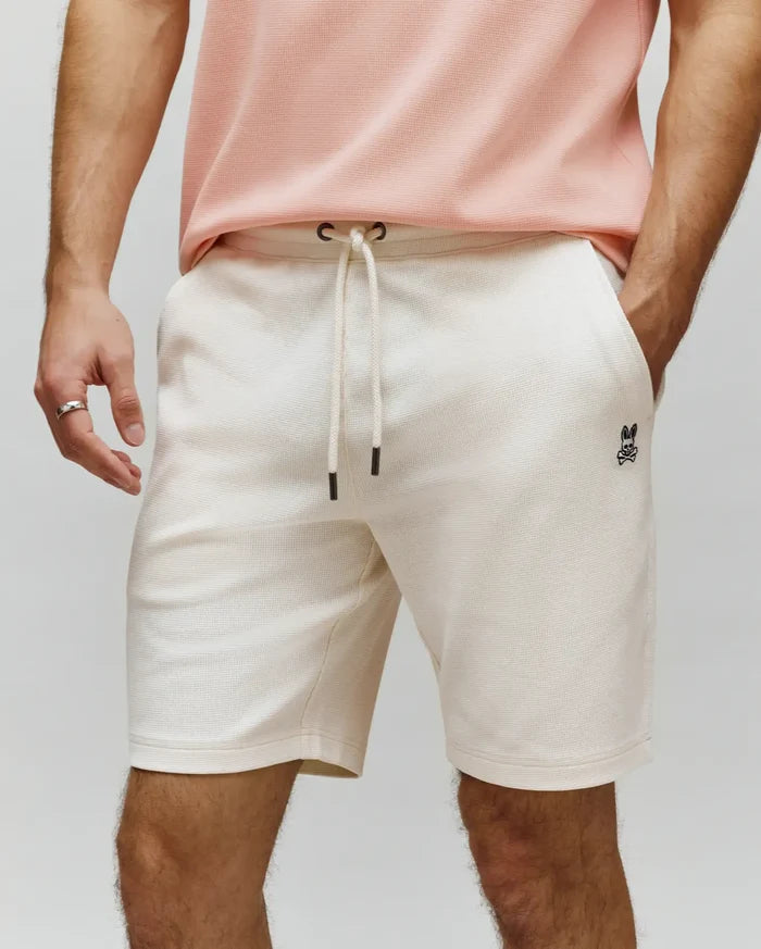 Mens Maxton Waffle Sweatshort in ecru, featuring a relaxed fit, waffle knit texture, drawstring waist, and a small embroidered black Psycho Bunny skull logo on the left thigh.