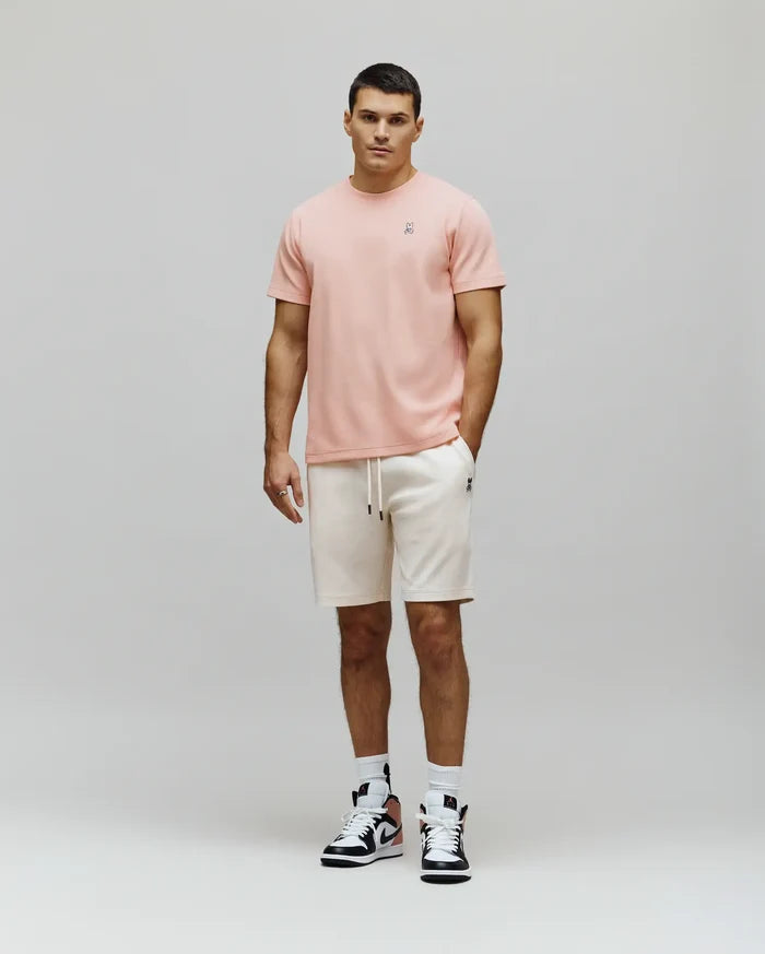 Textured pink t-shirt with an embroidered Psycho Bunny skull logo on the left chest, styled with off-white MENS MAXTON WAFFLE SWEATSHORT featuring a waffle knit, drawstring, and a small embroidered bunny skull.