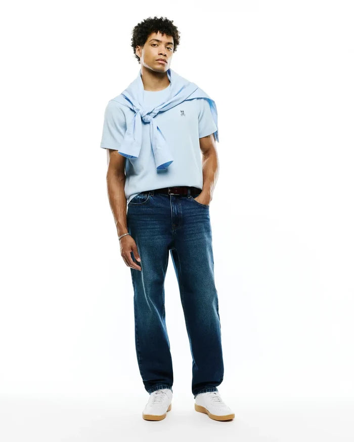 Light blue Mens Maxton Waffle Tee featuring a small embroidered Psycho Bunny skull logo on the left chest, styled with dark wash denim jeans and a light blue sweater.