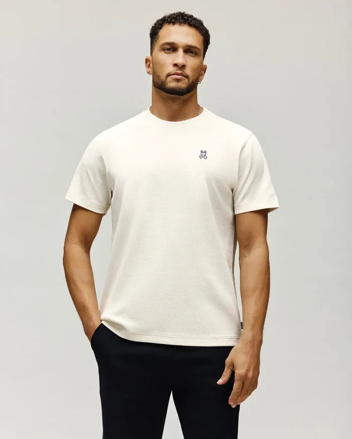 Mens Maxton Waffle Tee in cream, featuring a classic fit and waffle knit texture. Small embroidered Psycho Bunny skull logo with white and blue accents on the left chest.