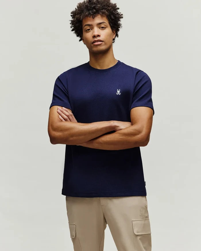 Mens Maxton Waffle Tee, a navy blue classic fit t-shirt with a waffle knit texture, featuring a small, embroidered white Psycho Bunny skull logo on the left chest.