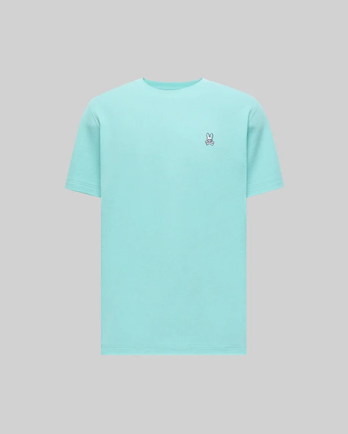 Mens Maxton Waffle Tee in aqua blue, featuring a classic fit and a textured waffle knit fabric. Small embroidered Psycho Bunny skull logo on the left chest with white, black, and red accents.