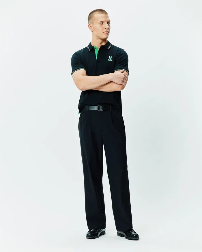Mens Nate Pique Polo, a classic fit black pique polo shirt with a vibrant green collar, white tipping on the collar and sleeves, and an embroidered Psycho Bunny skull logo on the left chest.