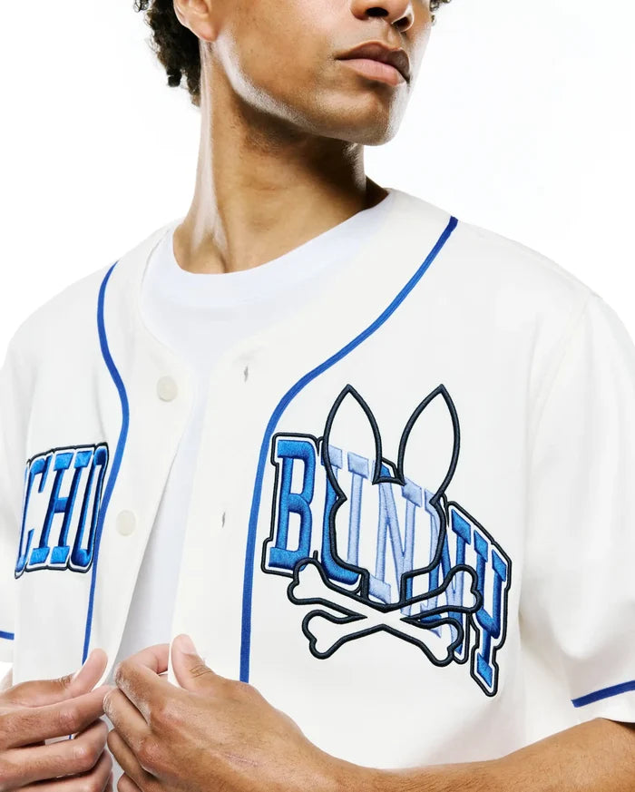 Mens Nathaniel Baseball Shirt in off-white, with royal blue piping and a large, textured blue embroidered Psycho Bunny skull and crossbones logo with PSYCHO BUNNY text across the chest, in a classic fit.