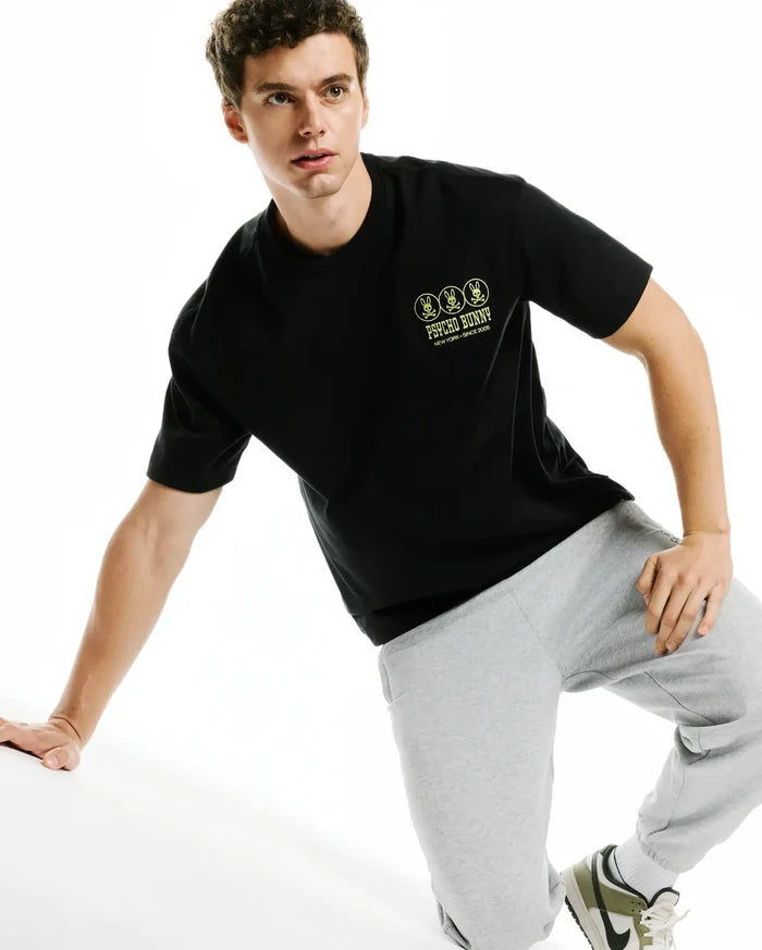 Men's Nathaniel Oversized Pima Tee, a black jersey knit t-shirt featuring a relaxed fit and a small embroidered neon yellow triple bunny skull logo with Psycho Bunny text on the left chest.