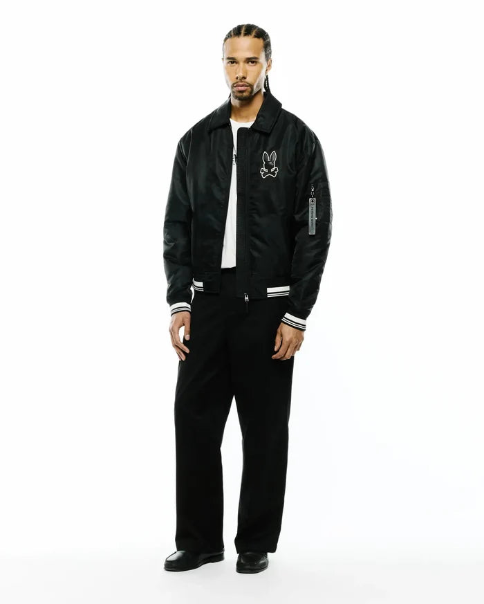Mens Nathaniel Satin Coach Jacket in black, featuring a relaxed fit, large white embroidered Psycho Bunny skull logo on the left chest, white striped ribbed cuffs, and a Psycho Bunny branded tag on the sleeve.