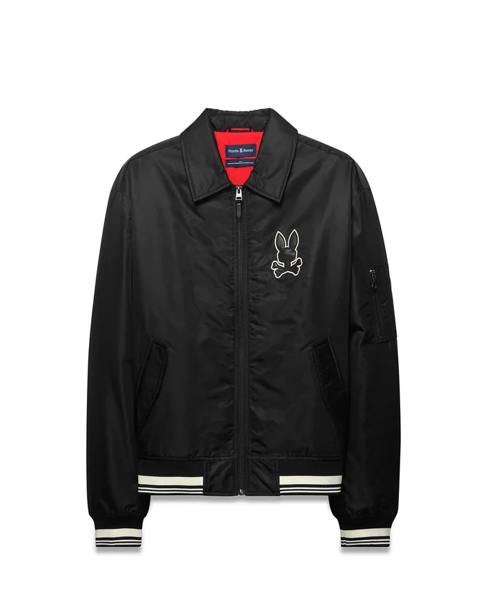 Mens Nathaniel Satin Coach Jacket, black with red lining, featuring a large white embroidered Psycho Bunny skull logo on the chest, white striped ribbed cuffs and hem, and a zippered sleeve pocket.