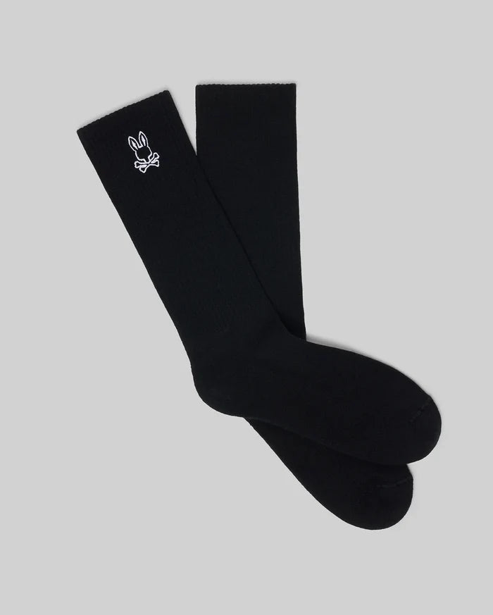 Mens New Classic Sport Sock, premium black ribbed knit crew socks featuring a small, crisp white embroidered Psycho Bunny skull logo prominently on the outer ankle cuff.