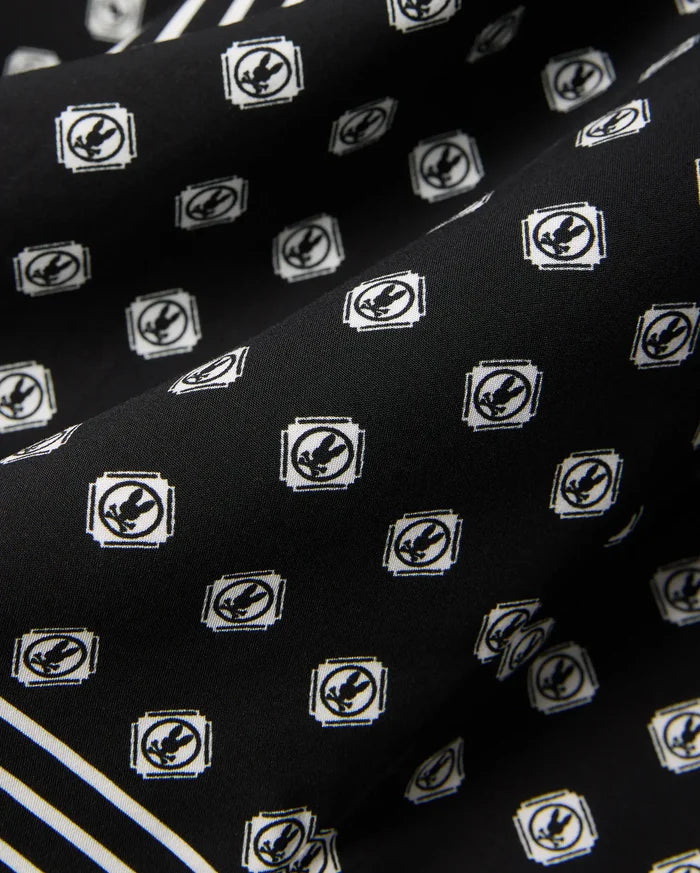 Black Mens Nick Tencel Shirt, a premium streetwear piece with a smooth Tencel weave, featuring an all-over white Psycho Bunny skull logo pattern and a bold white stripe accent.