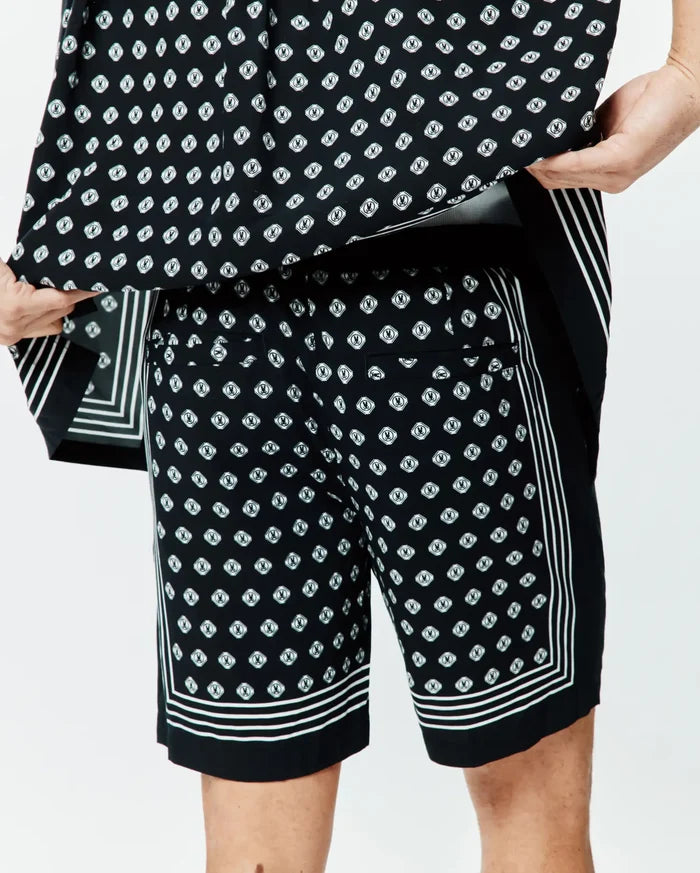 Mens Nick Tencel Short 7 in black, featuring a relaxed fit and smooth Tencel fabric. It has an all-over white Psycho Bunny skull logo diamond print, accented with bold white triple stripes along the side seams and hem.