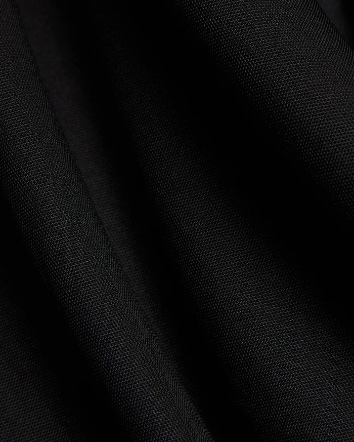 Mens Odin Zip Sport Polo in a rich black, featuring a visible premium pique knit fabric texture, characteristic of Psycho Bunny's refined streetwear style.