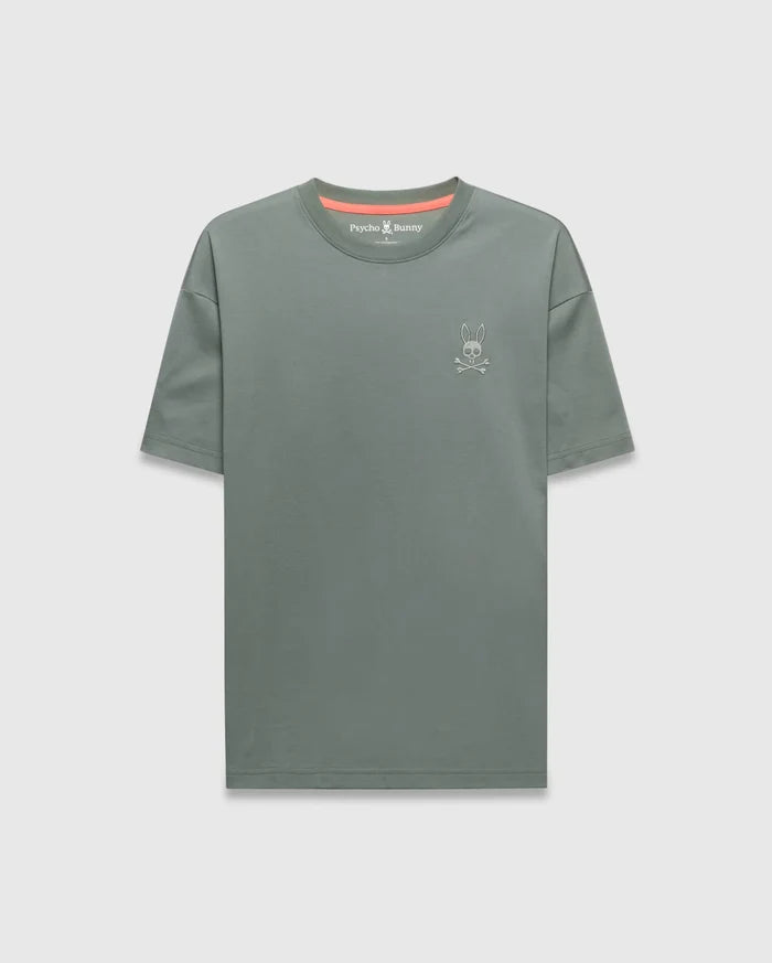 Mens Oscar Oversized Tee in muted sage green jersey knit, featuring a small white embroidered Psycho Bunny skull logo on the left chest and a vibrant coral inner collar accent.