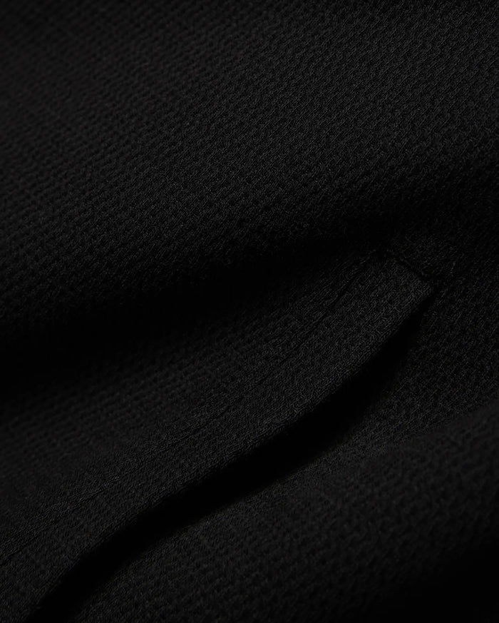 Mens Reilly Knit Coach Jacket in rich black, crafted from a premium, subtly textured knit fabric, embodying Psycho Bunny's refined streetwear style.