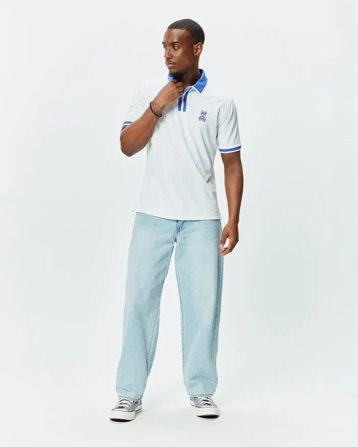 Mens Ridley Pique Polo in white pique, featuring a classic fit, blue striped collar and cuffs, and an embroidered blue Psycho Bunny skull logo on the left chest.