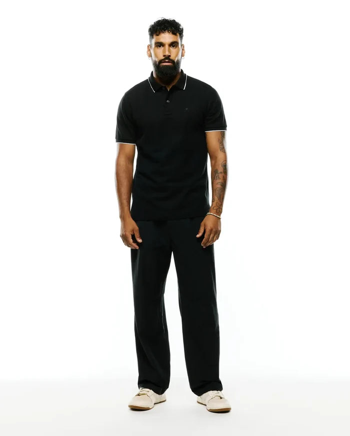 Premium Black Mens Ringston Pique Polo, classic fit, with white tipping on the collar and cuffs, featuring a small embroidered Psycho Bunny skull logo on the left chest.