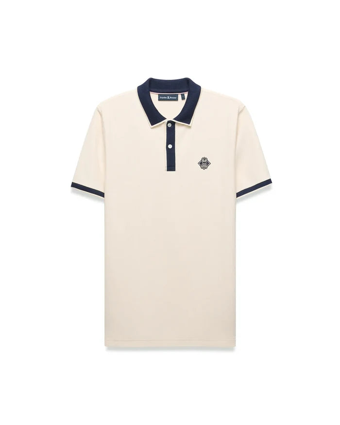 Mens Robin Pique Polo, a classic fit cream pique polo with navy blue ribbed collar, two-button placket, cuffs, and an embroidered Psycho Bunny skull logo on the left chest.