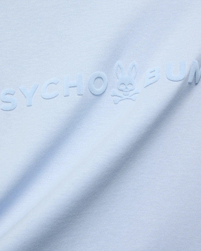 Mens Royce Graphic Tee, light blue jersey knit, featuring a large, tonal, raised velvety Psycho Bunny text logo with the iconic bunny skull on the chest.