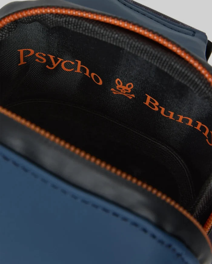 Mens Rubberized Crossbody in navy blue with a smooth rubberized texture and bright orange zipper. The black interior lining features a large orange Psycho Bunny text and skull logo print.