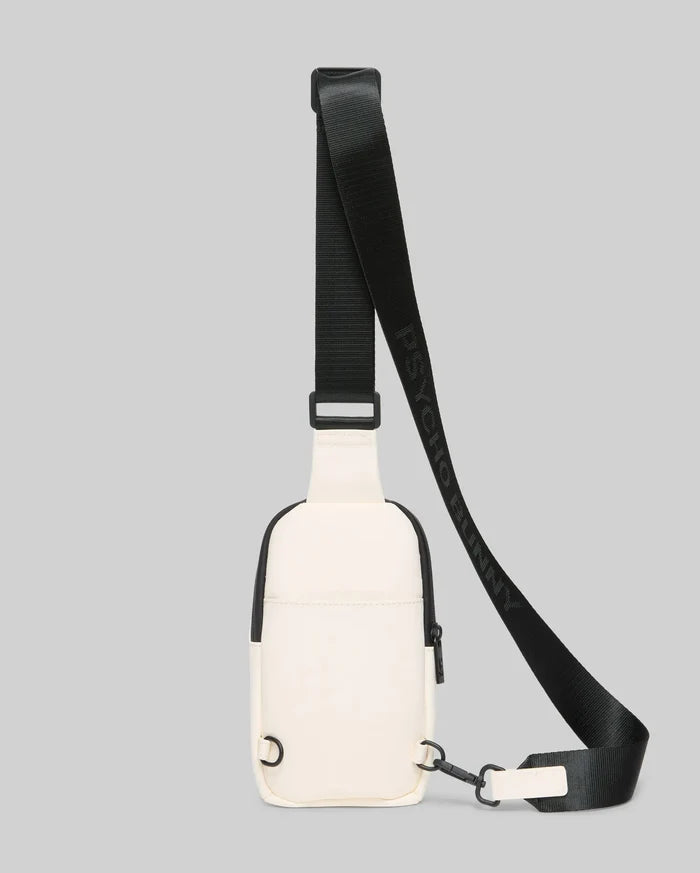 Mens Rubberized Crossbody in cream with sleek black trim, zippers, and hardware, featuring a smooth, durable texture and an adjustable black strap with repeated Psycho Bunny text branding.