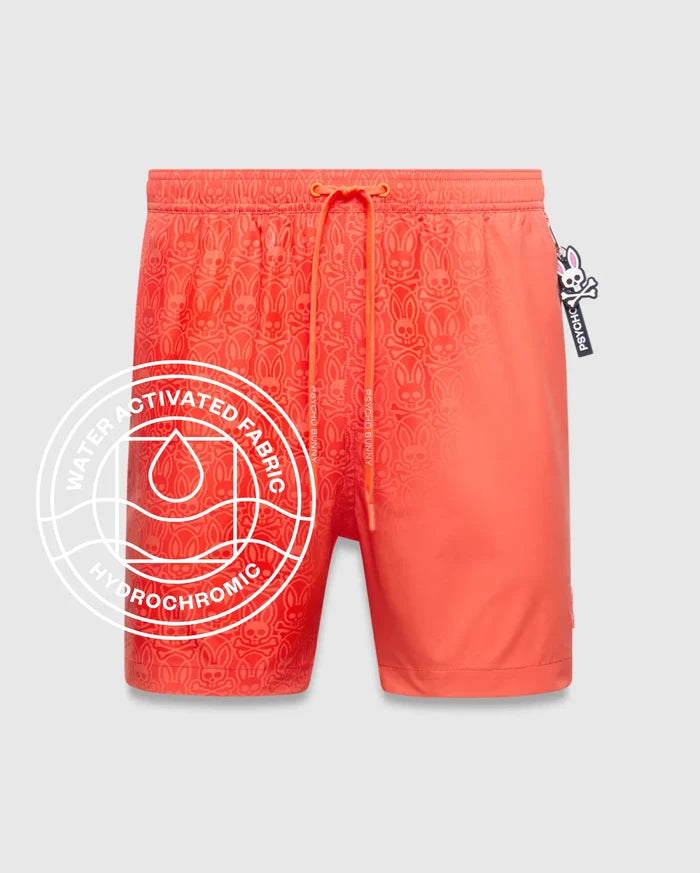 Mens Samos Hydrochromic Printed Swim Trunk in vibrant coral, featuring a water-activated, tone-on-tone Psycho Bunny skull pattern, orange drawstring, and a relaxed fit.