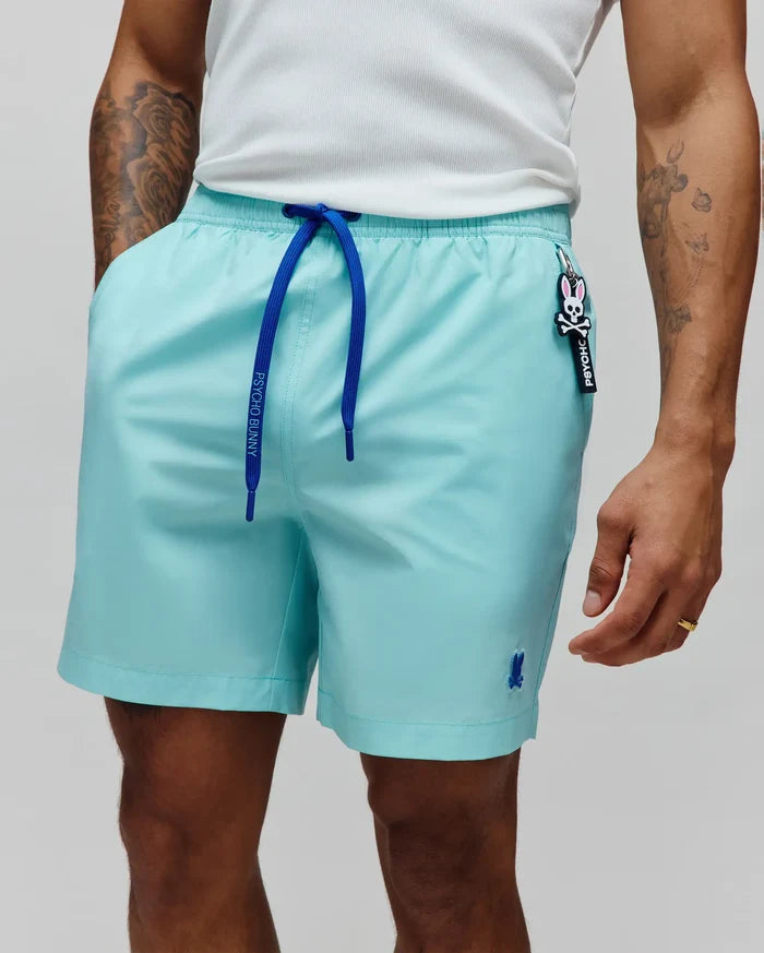 Mens Samos Hydrochromic Printed Swim Trunk. Aqua swim trunks featuring royal blue Psycho Bunny drawstrings, a small embroidered blue bunny skull logo, and a Psycho Bunny skull logo keychain.