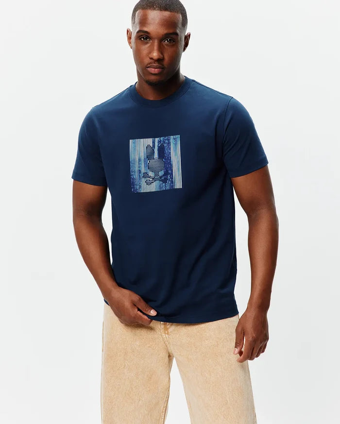 Mens Seamus Graphic Tee, a navy blue classic fit jersey t-shirt featuring a large chest graphic of the Psycho Bunny skull logo within a vibrant blue and white striped rectangle.