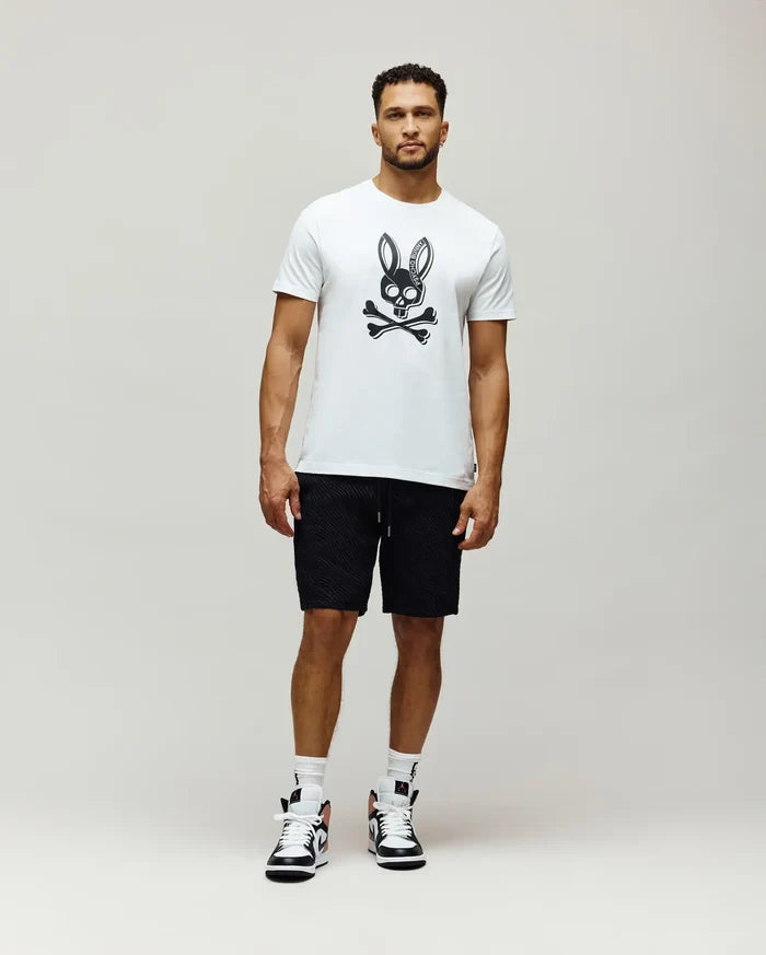 Mens Serge Embroidered Bunny Graphic Tee in white, featuring a large black Psycho Bunny skull graphic on the chest. Paired with black textured drawstring shorts.