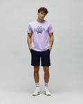Lavender jersey t-shirt with a large, distressed blue and purple Psycho Bunny skull logo on the chest, paired with classic fit navy Mens Shiro Twill Short.