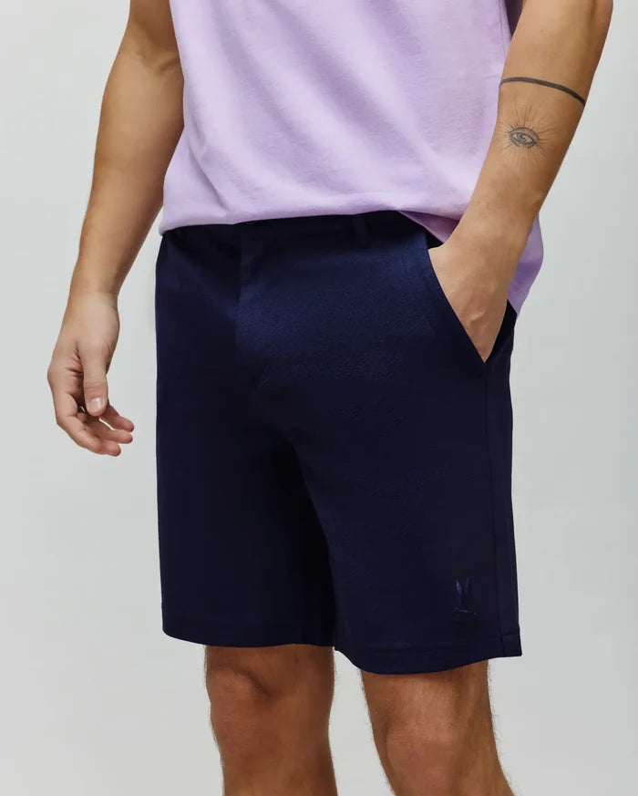 Mens Shiro Twill Short in dark navy blue, featuring a subtle diagonal twill texture, classic fit, and a small, tonal embroidered Psycho Bunny skull logo on the lower left leg.