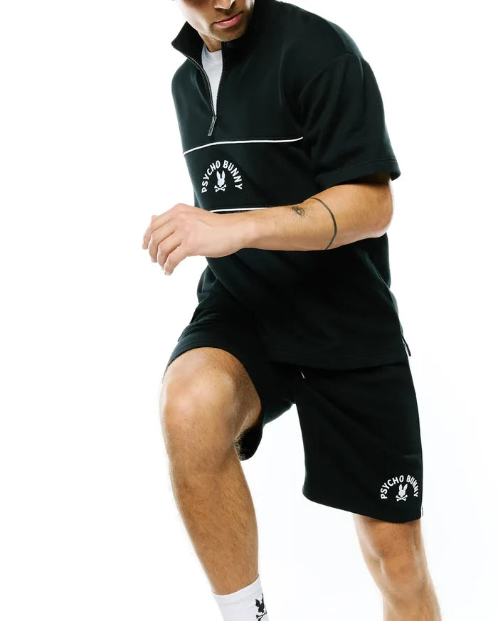 Black relaxed-fit short-sleeve quarter-zip top with white zipper, chest stripes, and embroidered Psycho Bunny skull logo. Black Mens Stevie Short with matching logo.