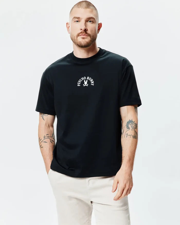 Mens Stevie Relaxed Fit Tee in black, featuring a small white Psycho Bunny skull and crossbones logo with arched text centered on the chest, made from smooth jersey knit fabric.