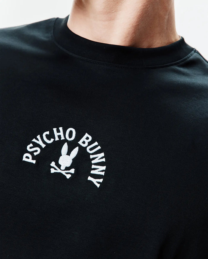 Mens Stevie Relaxed Fit Tee in black jersey knit, featuring a relaxed fit and a prominent white embroidered Psycho Bunny logo with the iconic bunny skull on the left chest.