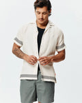 Mens Sunny Linen Shirt, off-white, relaxed fit, with a textured linen fabric, featuring black zigzag patterns on short sleeves and hem, plus a small embroidered Psycho Bunny skull logo on the left chest.
